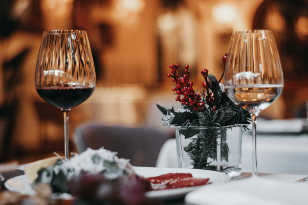 Weingläser mit rotem und weißem Wein auf festlich gedecktem Tisch mit Dekoration und unscharfem Hintergrund