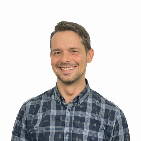 Lächelnder Mann mit kariertem Hemd vor weißem Hintergrund