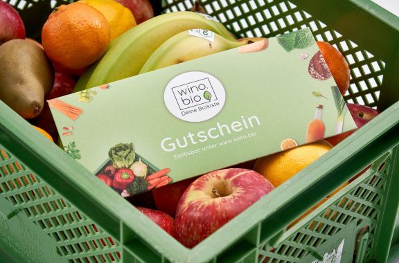 Grüner Obstkorb mit Gutschein von Wino.bio auf frischem Obst.