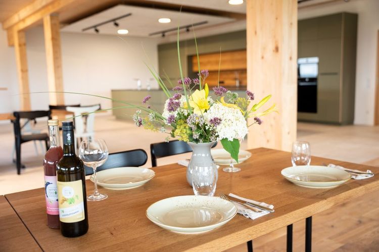 Esstisch mit Blumenvase, Weinflaschen und gedeckten Tellern in modernem Raum