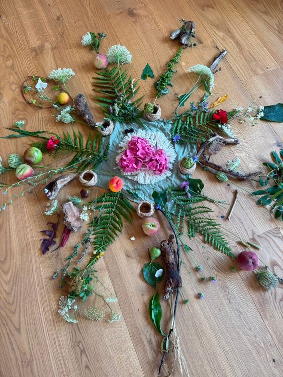 Natürliche Anordnung aus Blumen, Farnblättern, Früchten und Holzstücken auf Holzboden