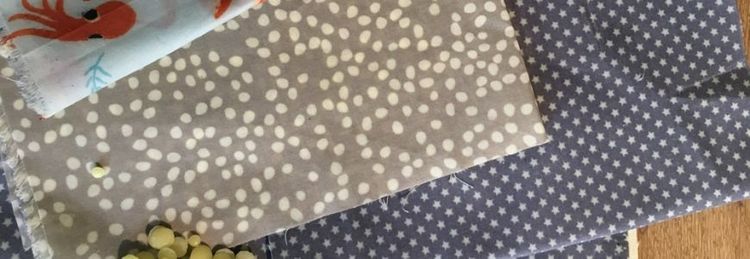 Mehrere Stoffstücke mit verschiedenen Mustern liegen auf einem Holztisch, darunter Punkte, Sterne und ein Oktopus-Motiv.