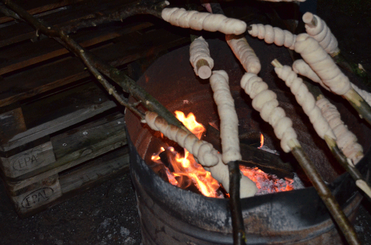 Teig auf Stöcken über einem offenen Feuer in einer Metalltonne zum Backen