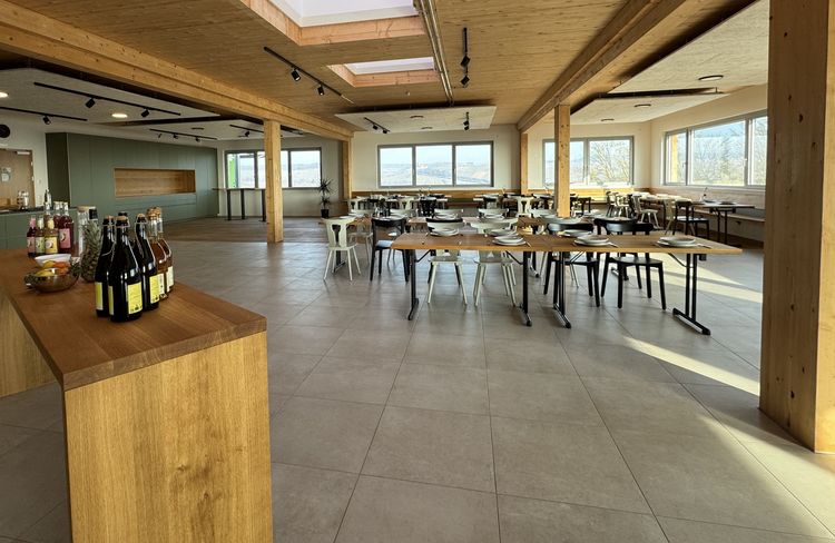 Moderner Speisesaal mit Holzelementen, gedeckten Tischen und großen Fenstern mit Blick auf die Landschaft