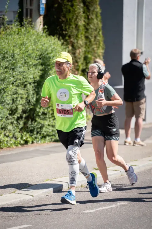 Zwei Läufer beim Straßenlauf, der vordere Mann trägt neongrünes Shirt und Nummer 6705