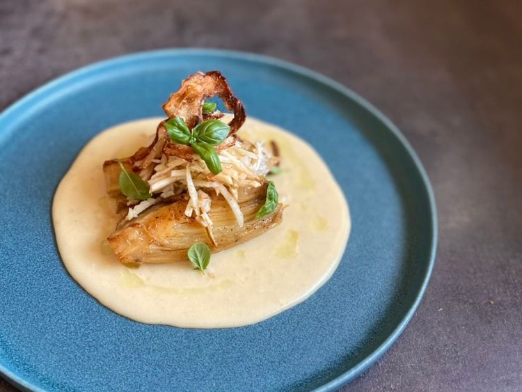 Garnierter Chicorée auf cremiger Sauce auf blauem Teller angerichtet