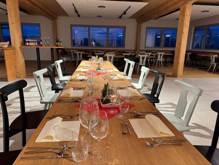 Gedeckter langer Holztisch mit weißen und schwarzen Stühlen in modernem Speisesaal am Abend.