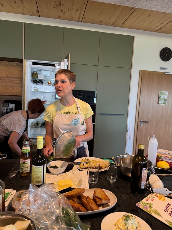 Frau mit Kochschürze bereitet Essen in moderner Küche mit offenem Kühlschrank vor