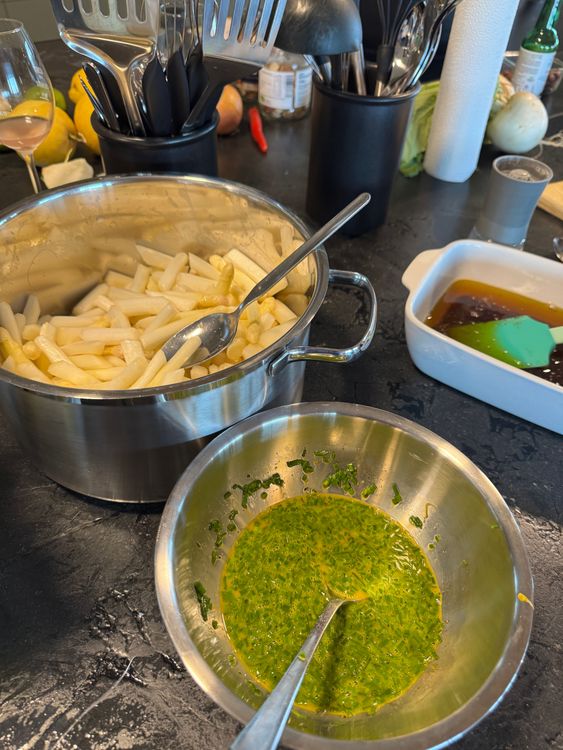 Frisch geschälter Spargel in Topf mit Kräutermischung in Schüssel auf Küchentheke
