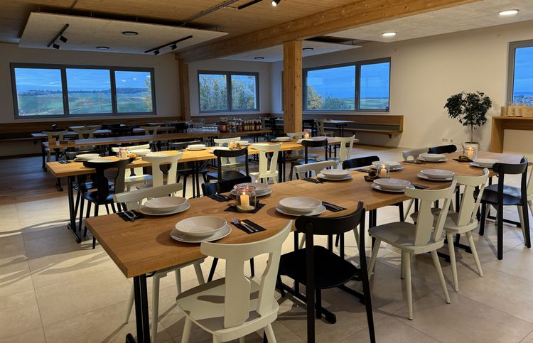Gemütlicher Speisesaal mit eingedeckten Tischen und Blick auf die Landschaft durch große Fenster