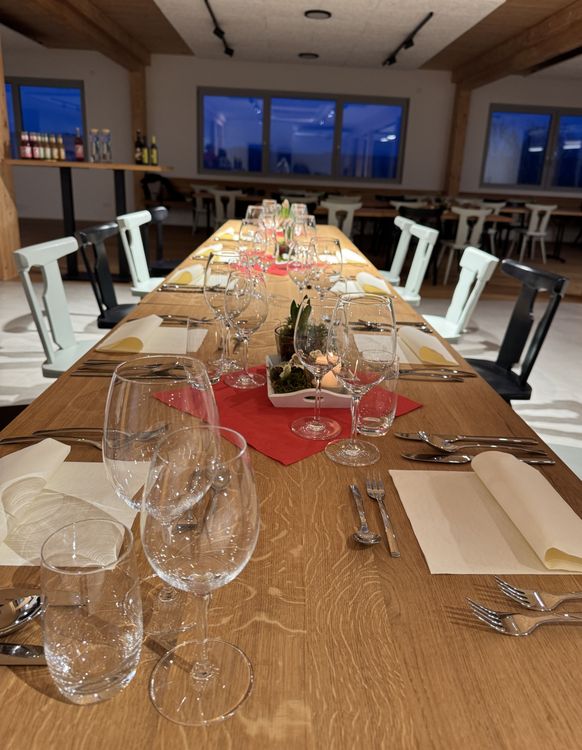 Eleganter Esstisch mit Glasgeschirr, Besteck und Servietten in modernem Innenraum bei Dämmerung.