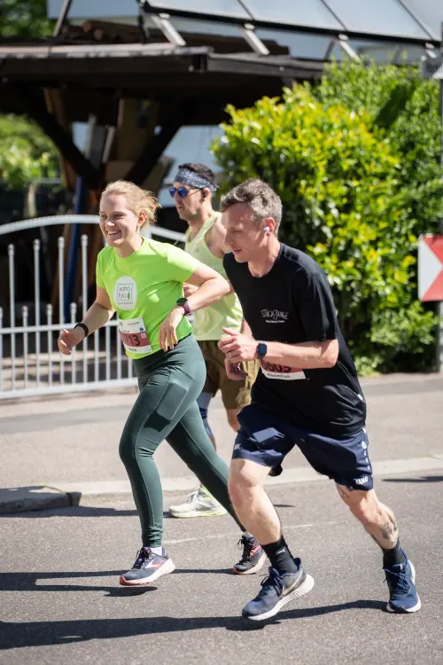 Drei Läufer nehmen an einem Straßenlauf teil bei sonnigem Wetter