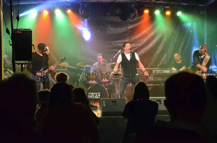 Live-Band spielt auf Bühne vor Publikum mit bunten Scheinwerfern im Hintergrund