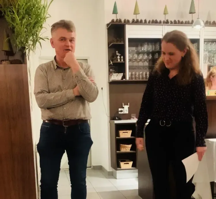 Mann und Frau stehen in einem Raum mit Bar und reden miteinander