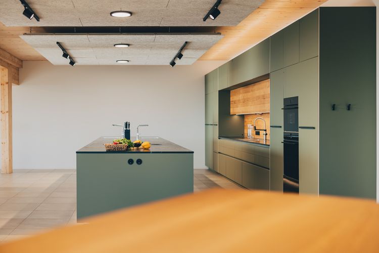 Moderne Küche mit grünen Schränken, Kücheninsel und Holzakzenten in hellem Raum
