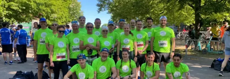 Gruppe von Menschen in grünen T-Shirts posiert nach einem Lauf im Park bei sonnigem Wetter