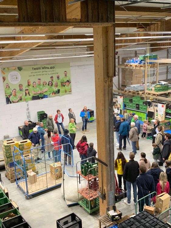 Gruppe von Menschen in Lagerhalle bei Führung vor Team Wino Bio Banner