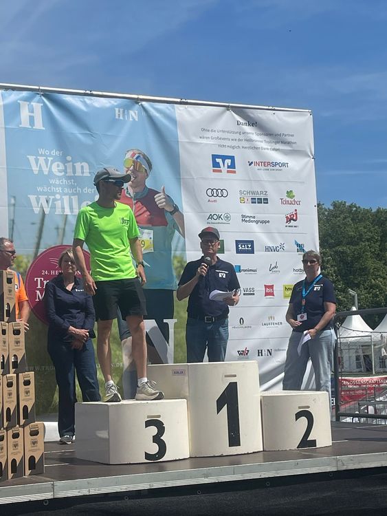 Siegerehrung beim Heilbronner Trollinger Marathon mit Podium, Personen und Sponsorenbanner im Hintergrund