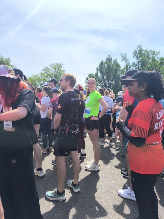 Gruppe von Menschen in Sportkleidung versammelt sich bei sonnigem Wetter für ein Lauf-Event im Freien.