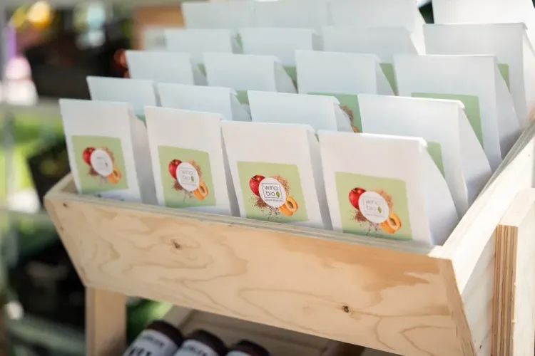 Weiße Bio-Samenpakete in einem Holzregal mit pflanzlichen Motiven auf Etiketten