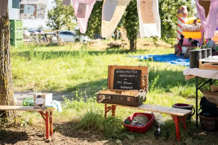 Koffer mit handgeschöpftem Büttenpapier aus Altpapier und Regenwasser im Freien auf einer Holzbank
