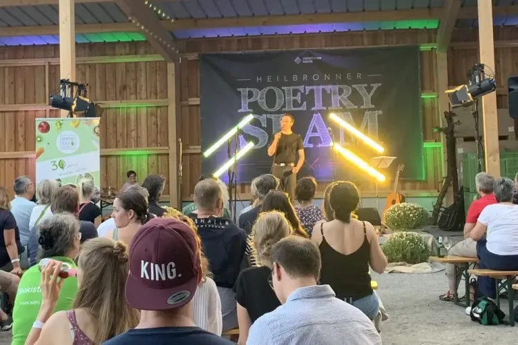 Publikum hört einem Vortragenden beim Heilbronner Poetry Slam in einer Scheune zu