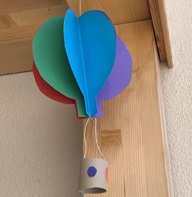 Bunter Papier-Heißluftballon mit Schnur hängend an Holztürrahmen