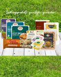 Biologische Lebensmittel und Snacks auf Holztisch vor grünem Gras mit Text Lieblingsprodukte genießen